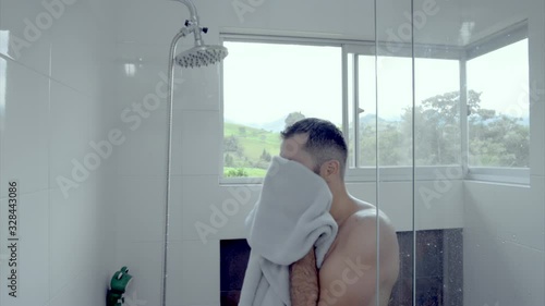 MAN IN THE BATHROOM DRYING WITH A TOWEL AFTER SHOWER BEARDED YOUNG GUY IN A LUXURY HOME photo