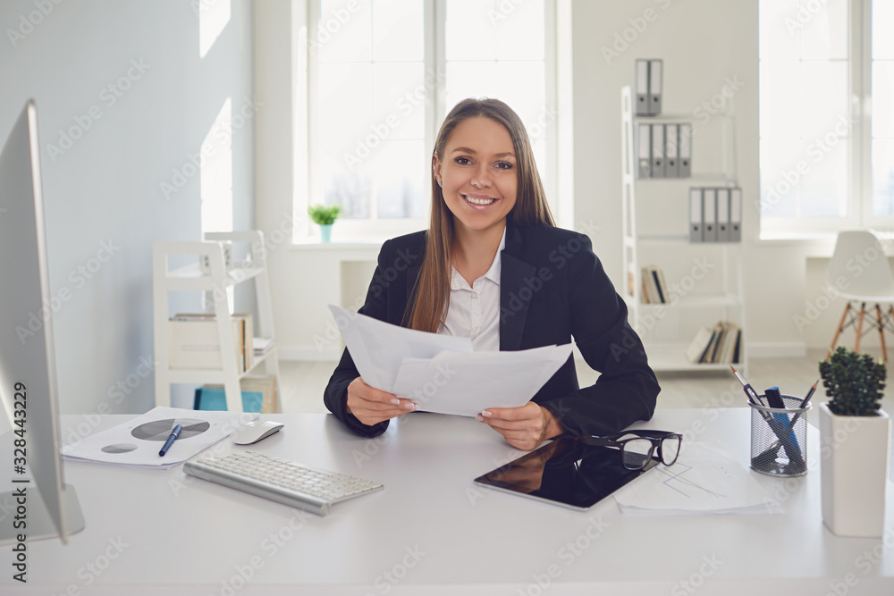 Happy businesswoman with documents in hands sitting at table