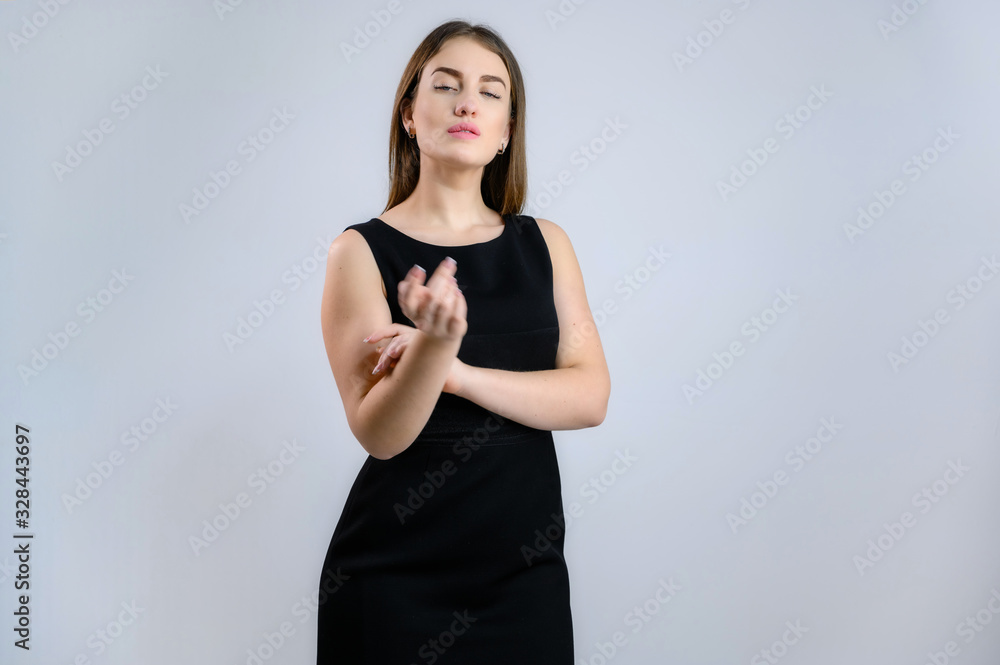 A woman is talking to the camera. Photo of a pretty girl in a black dress on a white background. A woman is talking to the camera. Photo of a pretty girl in a black dress on a white background.