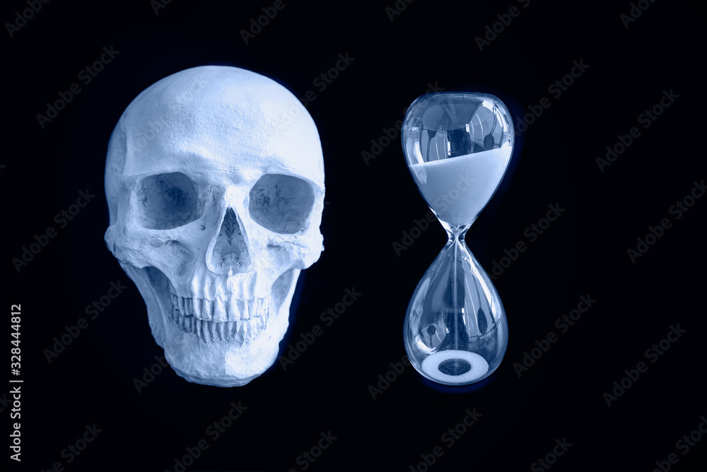 The skull of a dead man with an hourglass(sand watch) isolated black background