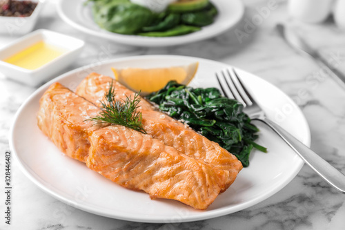 Tasty salmon with spinach and lemon on table