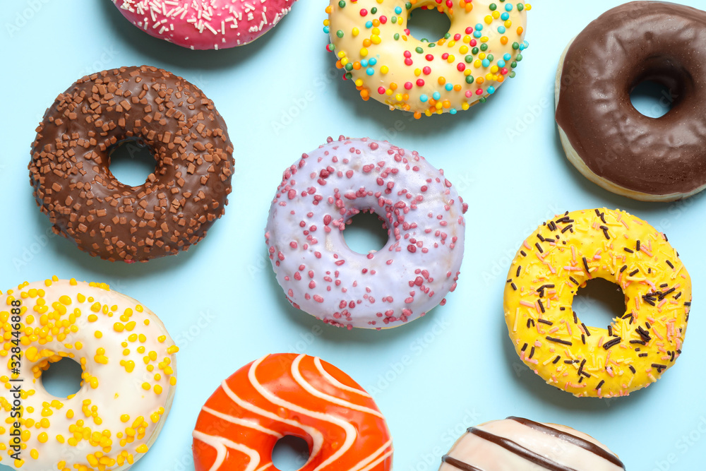 Delicious glazed donuts on light blue background, flat lay