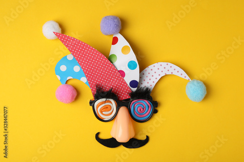Funny face made of party items on yellow background, flat lay. April Fool's Day photo