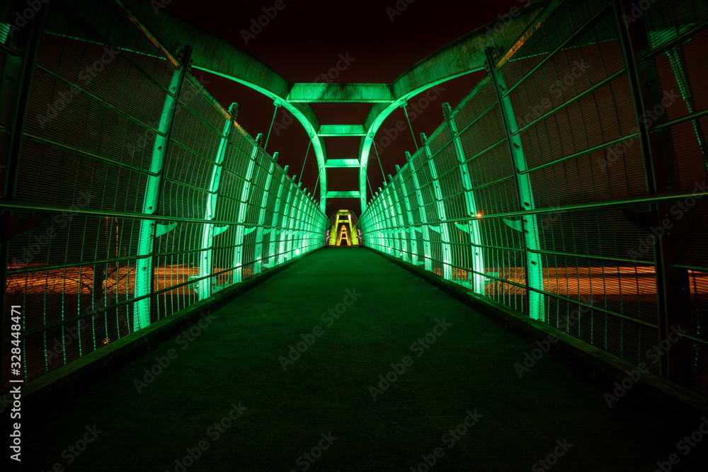 Green LEDs illuminate pedestrian walkway over highway at night