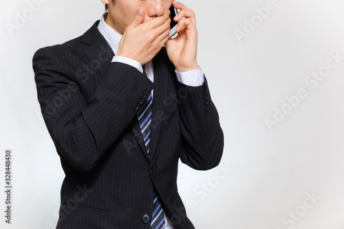 スマートフォンで話すスーツ姿の男性 小声 内緒 ビジネスマン ビジネスパーソン Stock Photo Adobe Stock