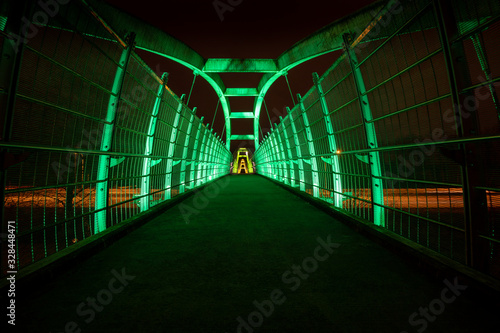 Obraz na płótnie Green LEDs illuminate pedestrian walkway over highway at night w salonie