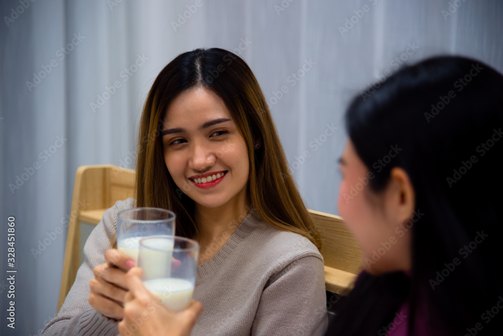 Young Asian beautiful woman enjoy drink a glass of milk on bed with happy mood in bedroom at night time Young Asian beautiful woman enjoy drink a glass of milk on bed with happy mood in bedroom at night time