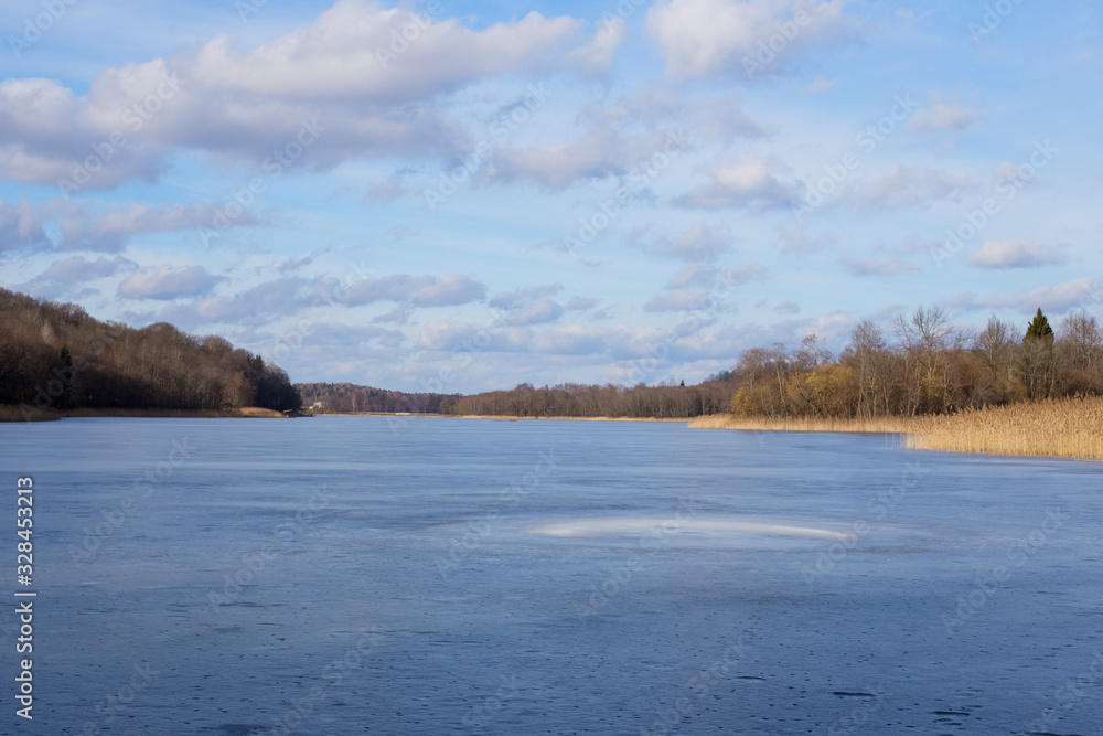 Landscape of a calm winter lake and its coastal part. Winter lake background