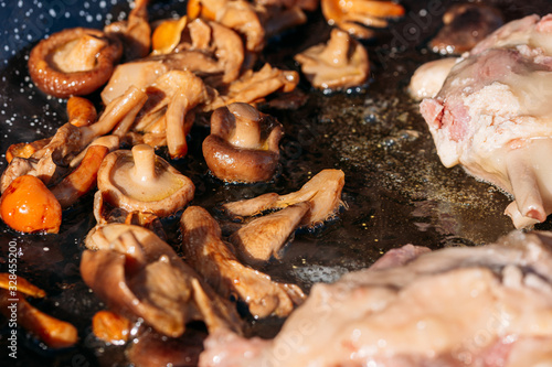 mushrooms and duck magret frying with hot olive oil in the foreground. Food background