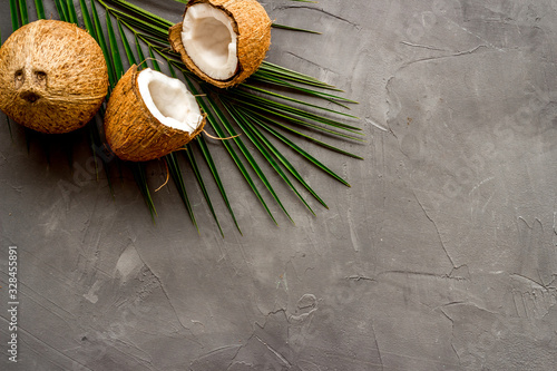 Coconuts and leaves - tropical still life on grey background top-down copy space