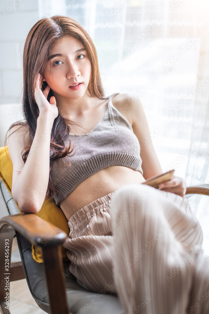 young beautiful Asian woman sitting on blue sofa and reading web by tablet at living room in the morning young beautiful Asian woman sitting on blue sofa and reading web by tablet at living room in the morning