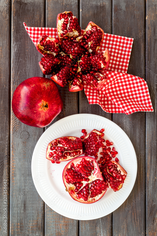 Cut pomegranate with ripe seeds on dark wooden background top-down Cut pomegranate with ripe seeds on dark wooden background top-down
