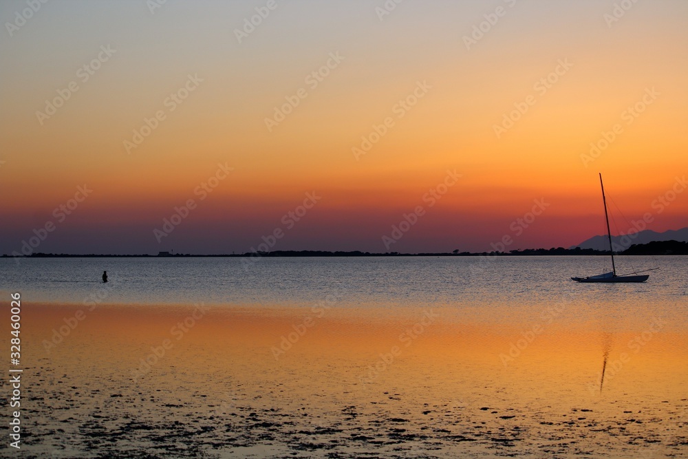 Fototapeta premium sailboat moored on the sea at sunset and headland on the background