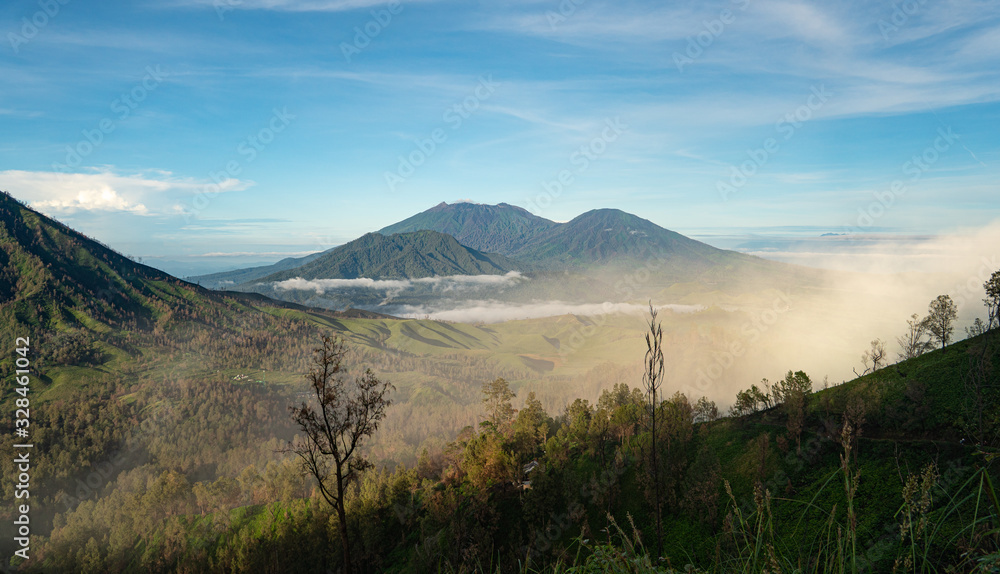 volcano Ruang next to Ijen covered in sulphur coming out uf Ijen. a mystic view early in the morning in Java, Indonesia