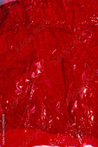 Thin sheet of red colour cellophane with shiny crumpled surface texture, Abstract background, Light & Shadow concept