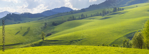 Green hills, meadows and mountain slopes. Spring rural landscape. Scenic panoramic view.