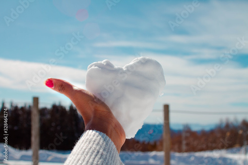 woman with snowy builed heart in her hands on the snow photo