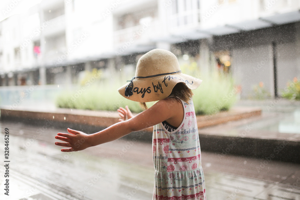 child in dress and straw hat got wet in rain