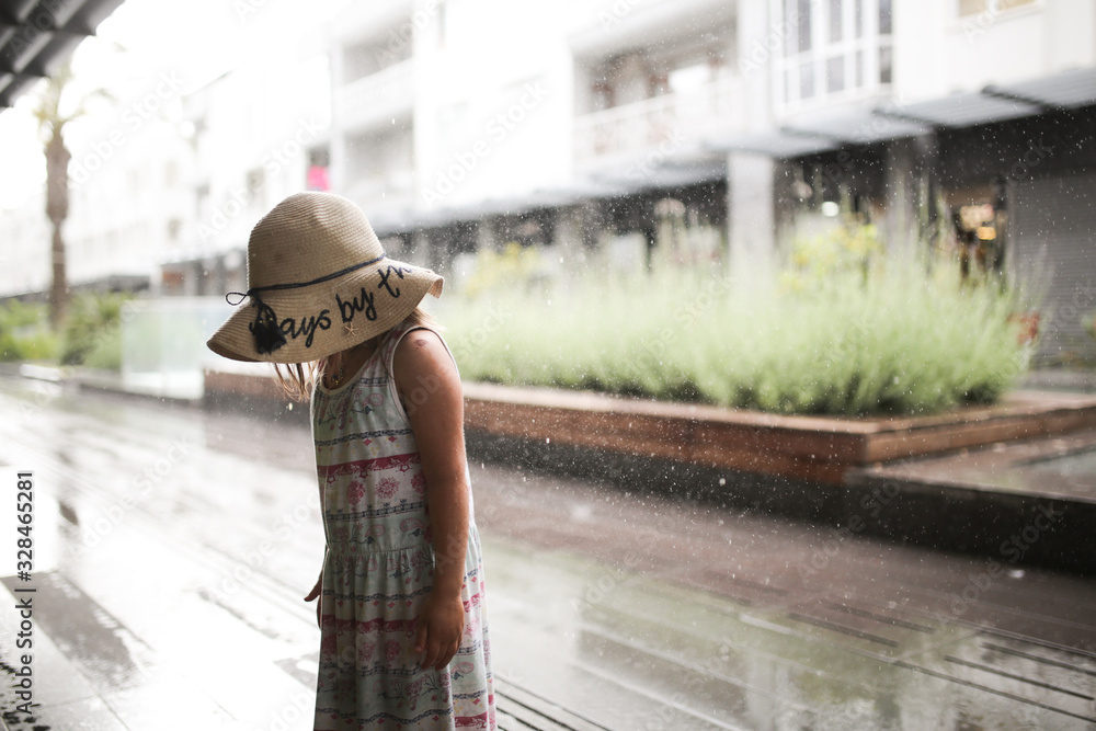 child in dress and straw hat got wet in rain