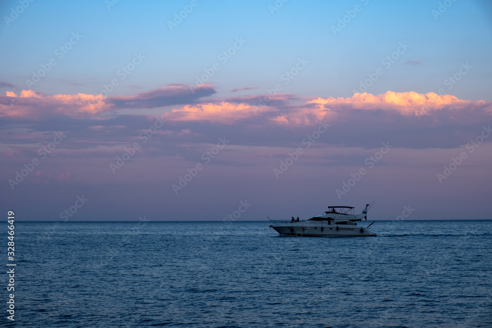 Luxury yacht on mediterranean sea at evening time with beautiful gold cloudy sky background.