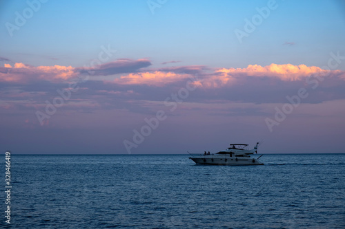 Luxury yacht on mediterranean sea at evening time with beautiful gold cloudy sky background. © Adil