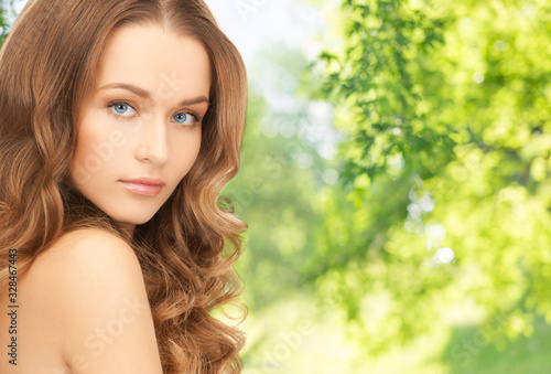 people, beauty and skin care concept - beautiful woman with curly hair over green natural background