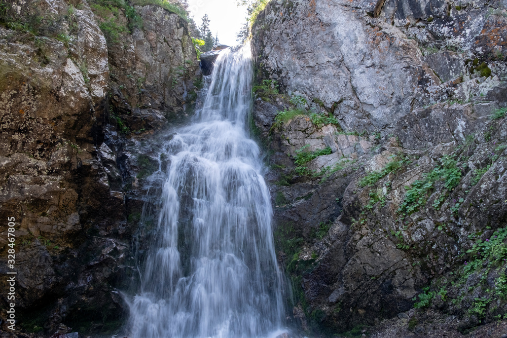 Mountain tourism, hiking. Beautiful landscape with small waterfall among rocky mountains.