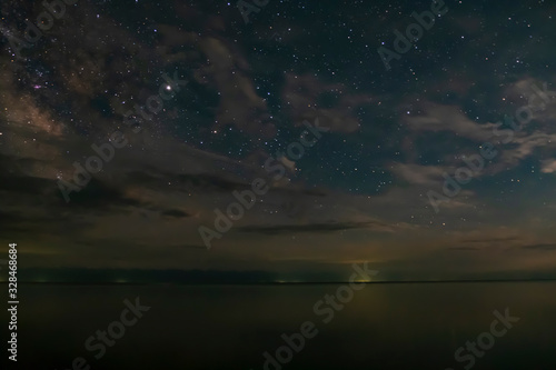Cloudy blue night sky with many stars and lake. Lake in the night.