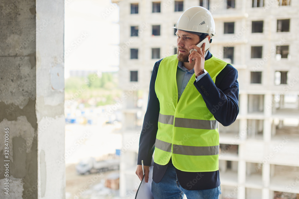 An engineer in a helmet talks on the phone.