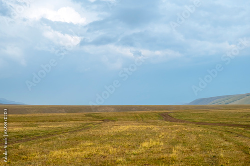 Scenic mountain valley landscape with rain clouds background. Nature background. Rural scenery. Dramatic scene. Autumn background. Mountain valley. Assy plateau in Kazakhstan.