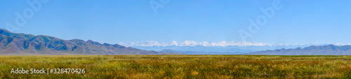 Mountain range landscape with meadow. Sunset view. Amazing natural background. Mountain hiking. Khan Tengri peak.