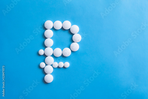 Ruble sign made of round pills on blue background. Pharmacy business, medicine pill concept.