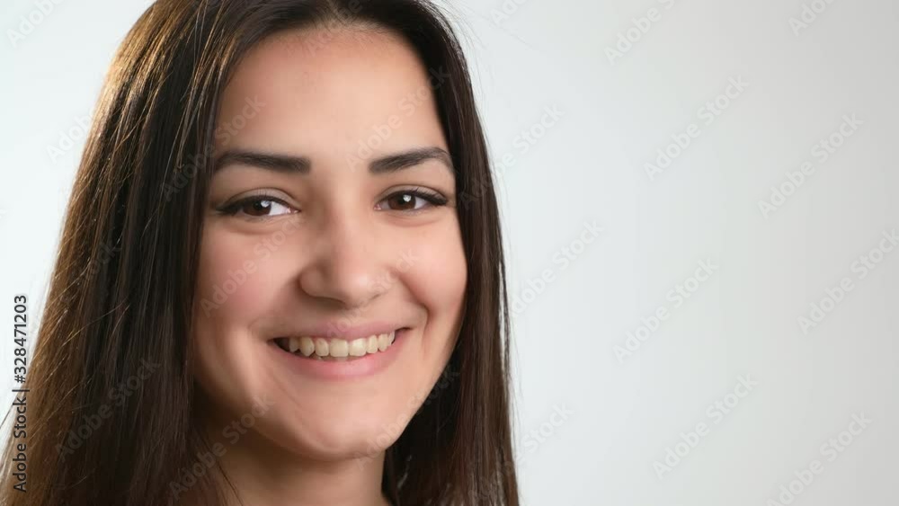 Happy long-hair brunette girl standing and smiling cheerily in a white studio Happy long-hair brunette girl standing and smiling cheerily in a white studio