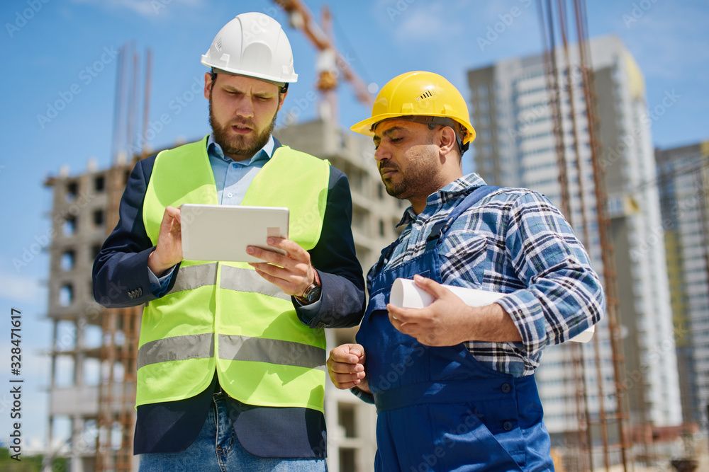 Two engineers discuss work related questions together. Two engineers discuss work related questions together.