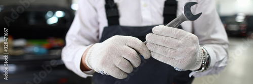 Billede på lærred Focus on automechanic male hand in white gloves holding and showing utility for fixing car at camera