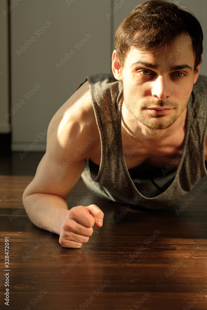 Portrait of a handsome man doing exercises plank at home