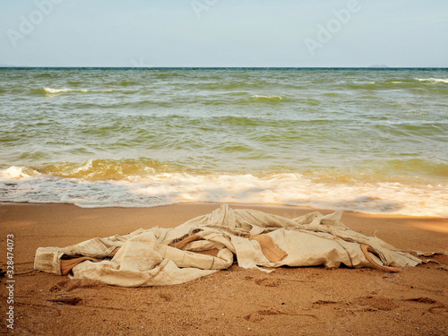 A white big bag is left abandoned on the beach. Garbage, rubbish and waste management. Environmental awareness.