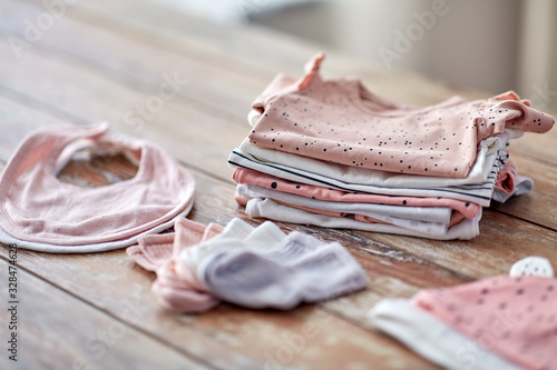 babyhood and clothing concept - baby clothes on wooden table at home photo