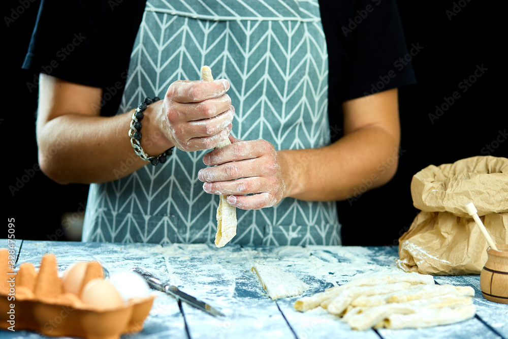 Obraz premium Closeup process making homemade pasta. Chef cook cutting with knife fresh dough for italian traditional pasta to thin ribbon. Italian cuisine recipe. Home cuisine. Husband cooking food on kitchen.