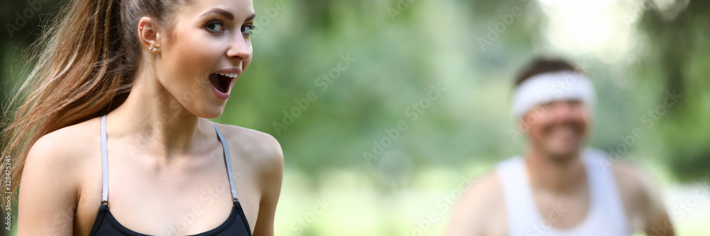 Portrait of wonderful sportswoman with collected long hair running in green park. Perfect model looking at camera with joyfulness. Sport and fitness concept Portrait of wonderful sportswoman with collected long hair running in green park. Perfect model looking at camera with joyfulness. Sport and fitness concept