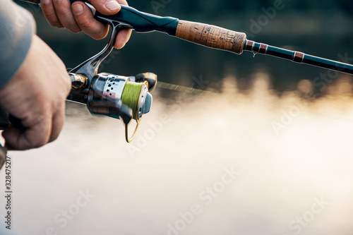 Fishing rod with a spinning reel in the hands of a fisherman.