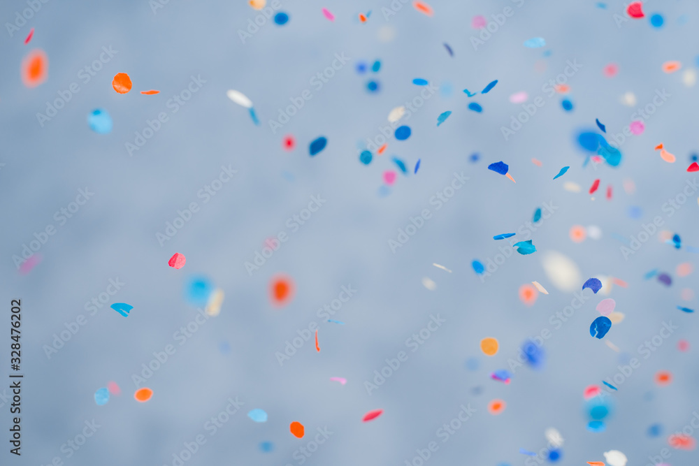 Colorful confetti falling on a holiday on a blue background - obrazy, fototapety, plakaty 