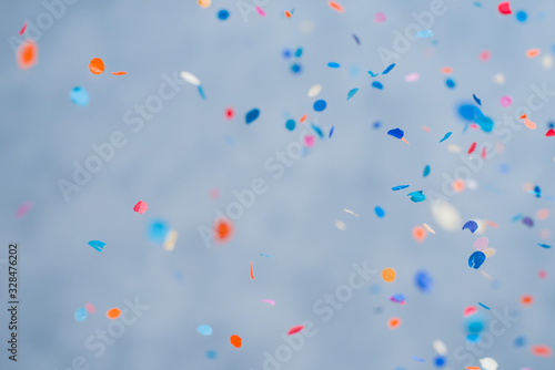 Colorful confetti falling on a holiday on a blue background