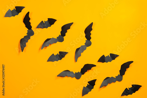 Halloween paper decorations concept. Black paper bats on a orange background. Halloween concept. © Adil