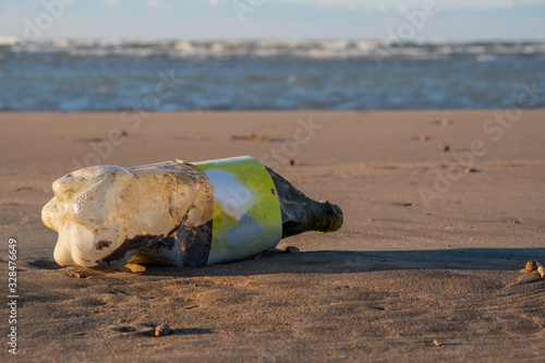 Old plastic bottles on a sandy beach. Enviroment pollution or problems concept.