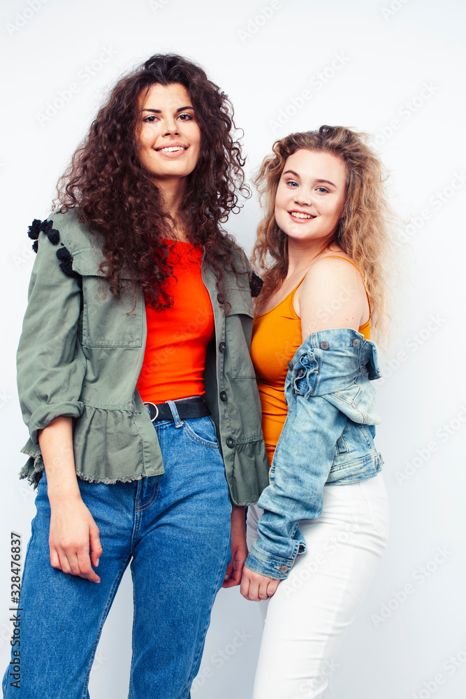 young pretty teenage girls friends with blond and brunette curly hairs posing cheerful isolated on white background, lifestyle people concept young pretty teenage girls friends with blond and brunette curly hairs posing cheerful isolated on white background, lifestyle people concept