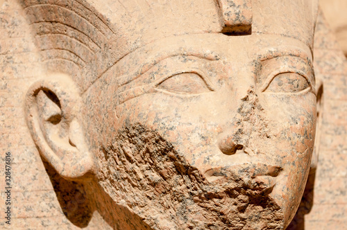 Full frame close-up of the damaged face of a stone sphinx in bright desert sun at the Allée des Sphinx in Karnak, Egypt