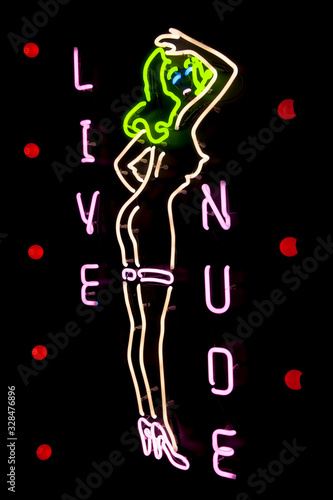 Nighttime view of glowing sign for live nude eriotic show featuring a woman with green hair outdoors 