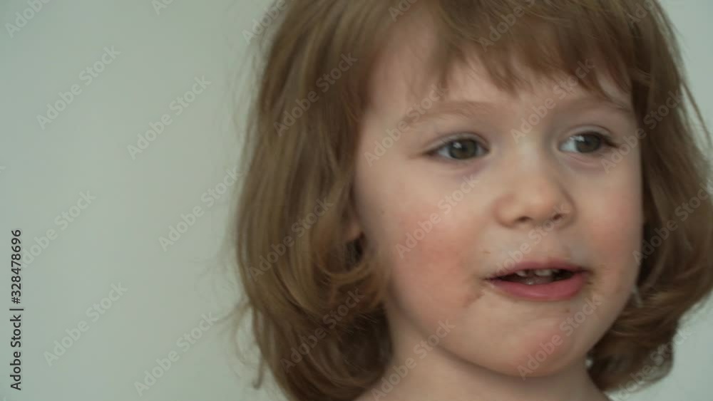 Portrait of little funny 3 year old girl eats with big appetite piece of tasty chocolate. Сhild got dirty with chocolate. Close up Portrait of little funny 3 year old girl eats with big appetite piece of tasty chocolate. Сhild got dirty with chocolate. Close up