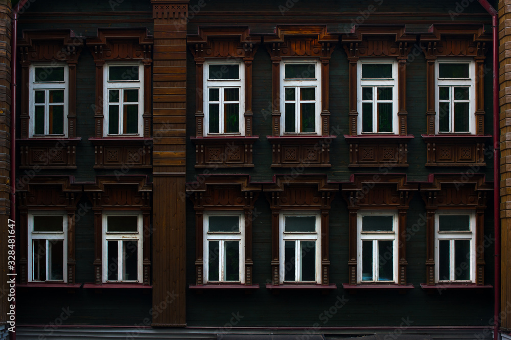  wall of brown wooden house with white windows